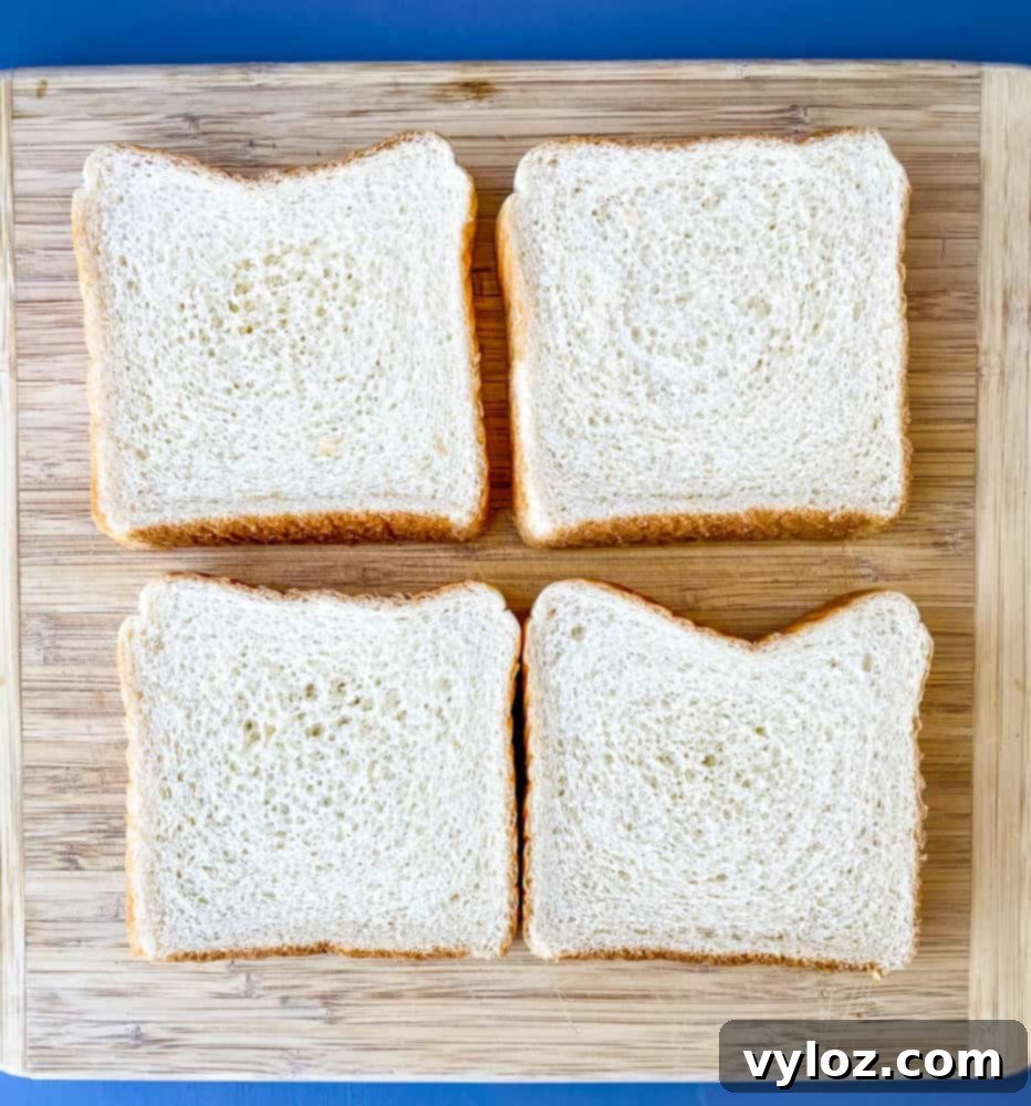 Four thick slices of Texas toast bread, perfectly suited for cutting into air fryer French toast sticks, arranged on a rustic wooden cutting board