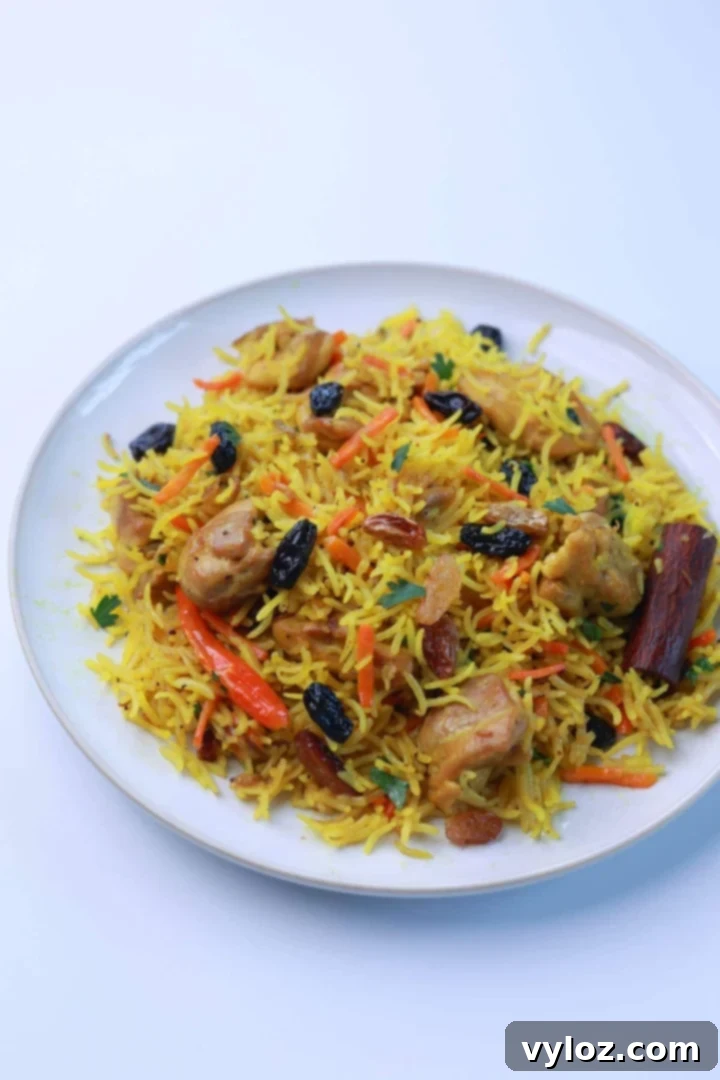 No-Fuss One-Pot Chicken Pilaf 2 A delicious serving of easy one-pot chicken pilaf on a white plate, garnished with parsley, showcasing the golden rice, tender chicken, and raisins.