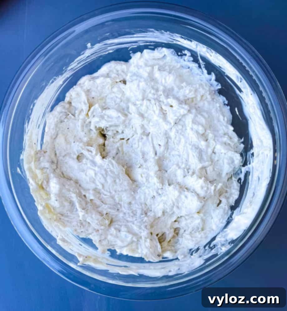 Crab rangoon dip in a mixing bowl, garnished with green onions.