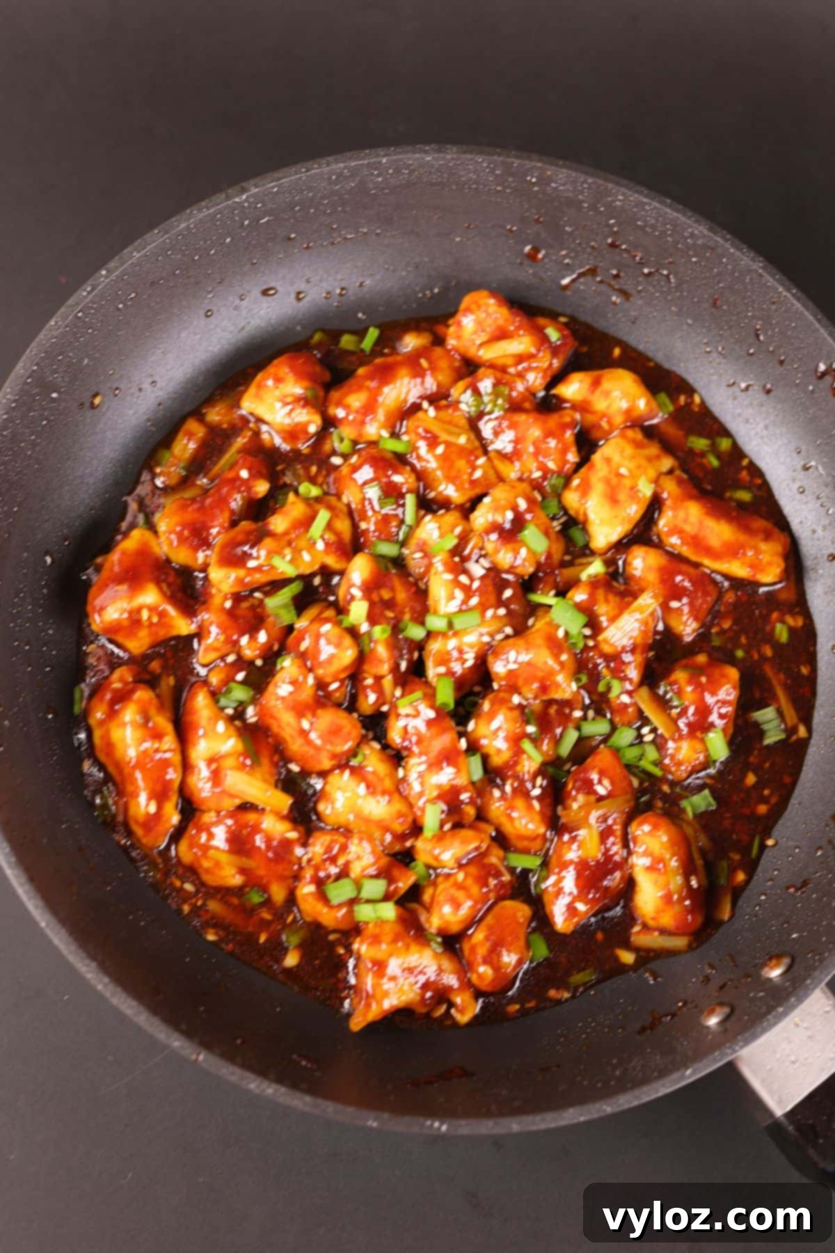 Chinese chicken in a black pan with savory garlic sauce.