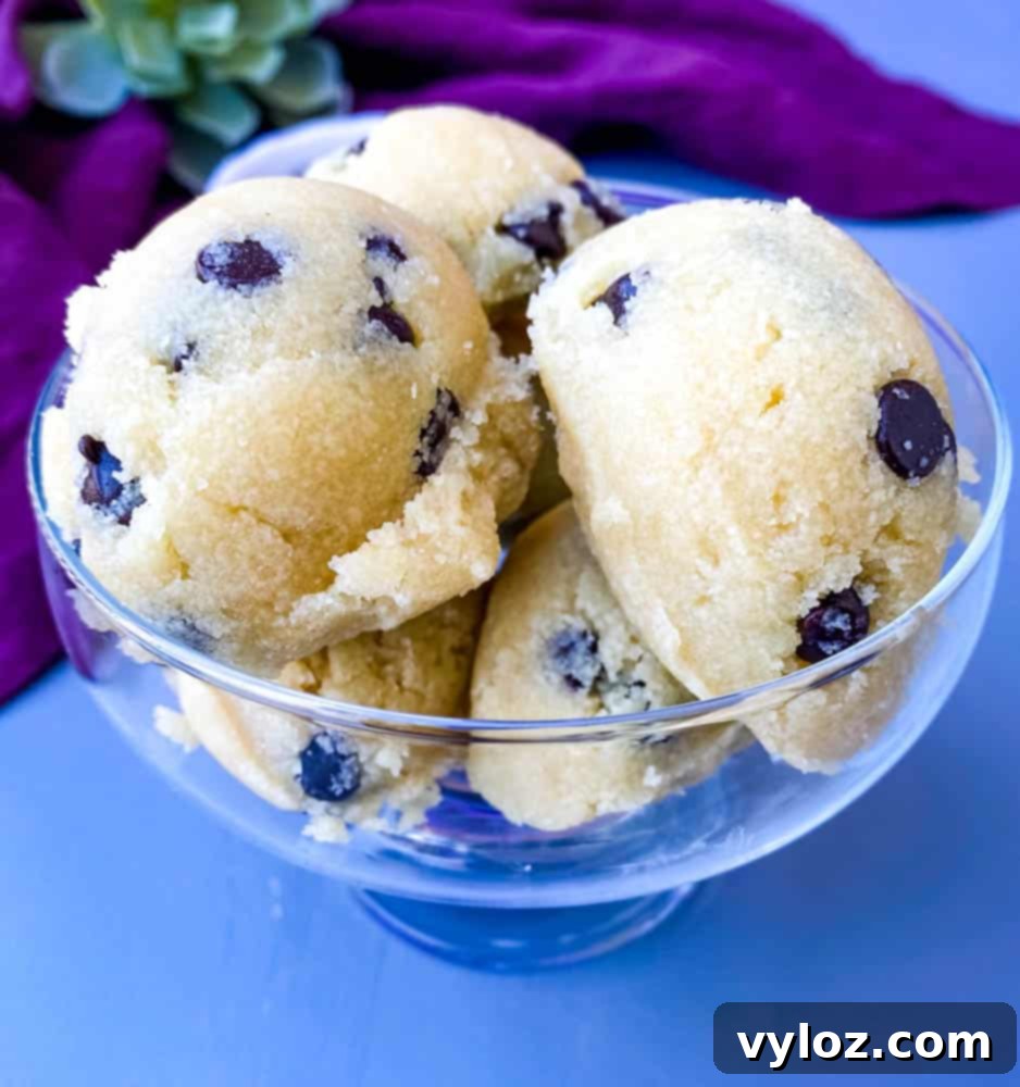 Individual keto low-carb chocolate chip cookie dough bites arranged artfully in a glass bowl with a soft purple napkin.