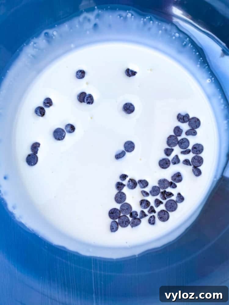 Effortless Sugar-Free Chocolate Mousse 4 Close-up of heavy cream and sugar-free chocolate chips in a clear glass bowl, ready for melting to make keto low carb chocolate mousse