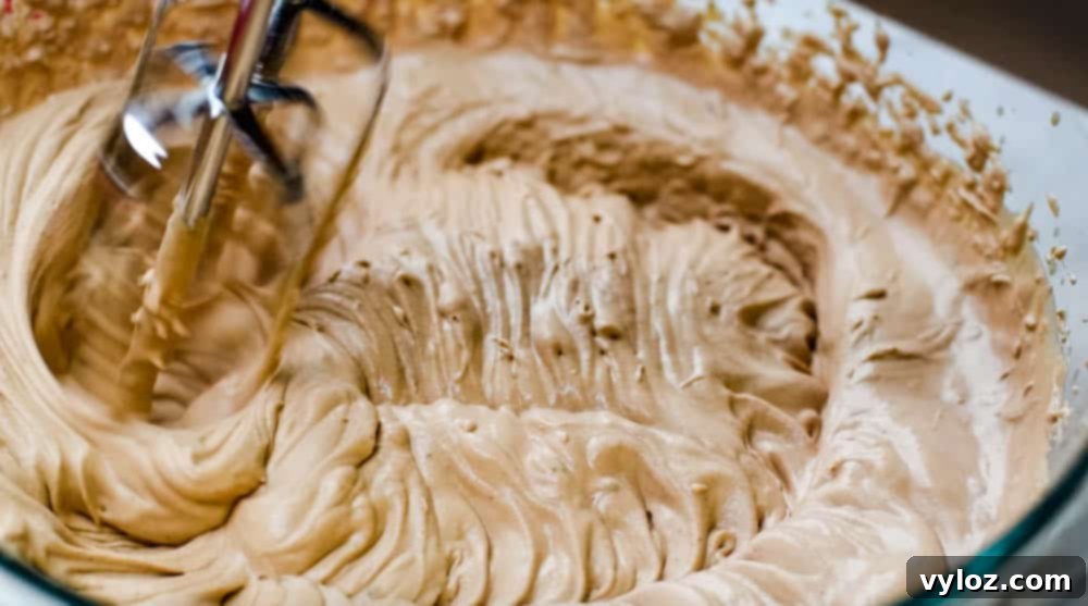 Effortless Sugar-Free Chocolate Mousse 7 Keto low carb chocolate mousse batter being beaten in a glass bowl with a hand mixer, showing developing stiff peaks
