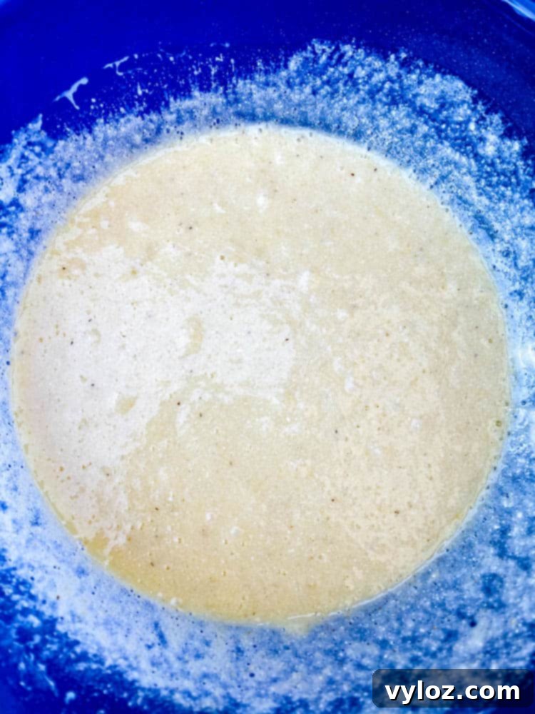 Crispy Air Fryer Cornbread 5 Close-up of air fryer cornbread batter in a glass bowl, showcasing its smooth consistency.