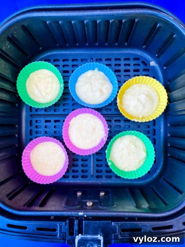 Crispy Air Fryer Cornbread 6 Air fryer cornbread muffin batter poured into silicone molds, placed inside an air fryer basket, ready to cook.
