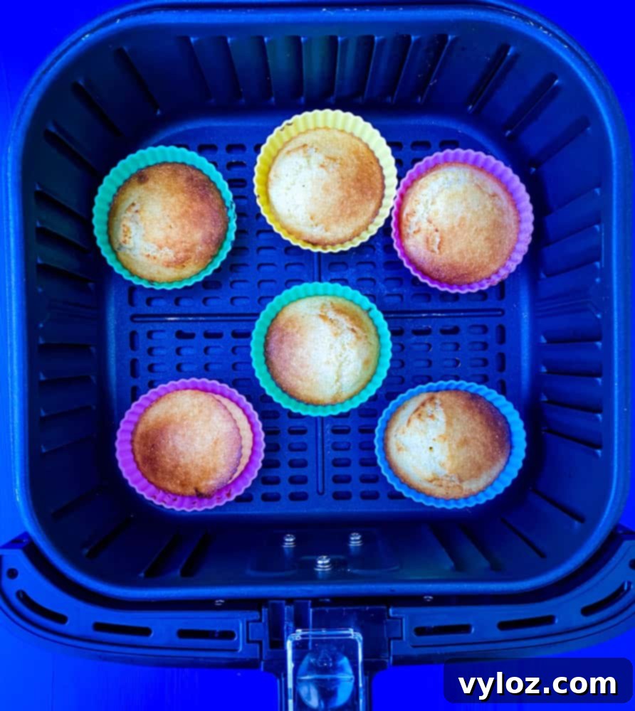 Crispy Air Fryer Cornbread 7 Freshly baked air fryer cornbread muffins in silicone molds, cooling in the air fryer basket.