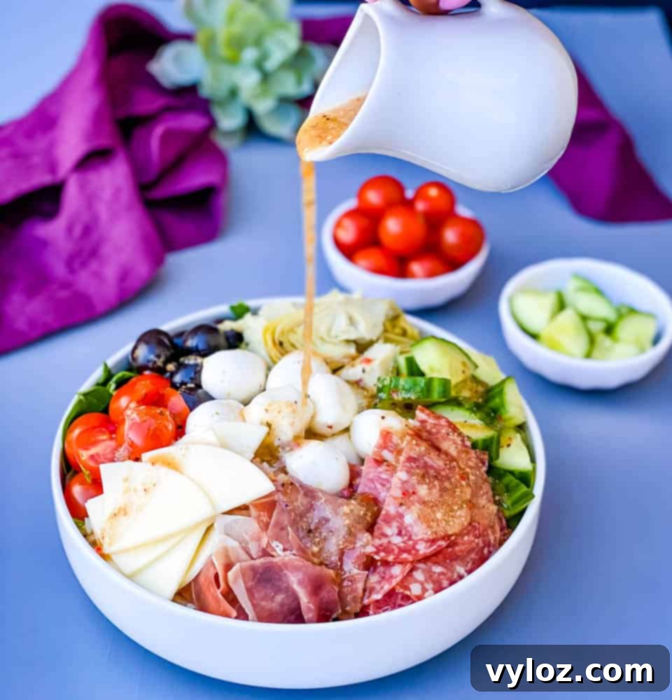 Italian dressing drizzled over antipasto salad in a white bowl