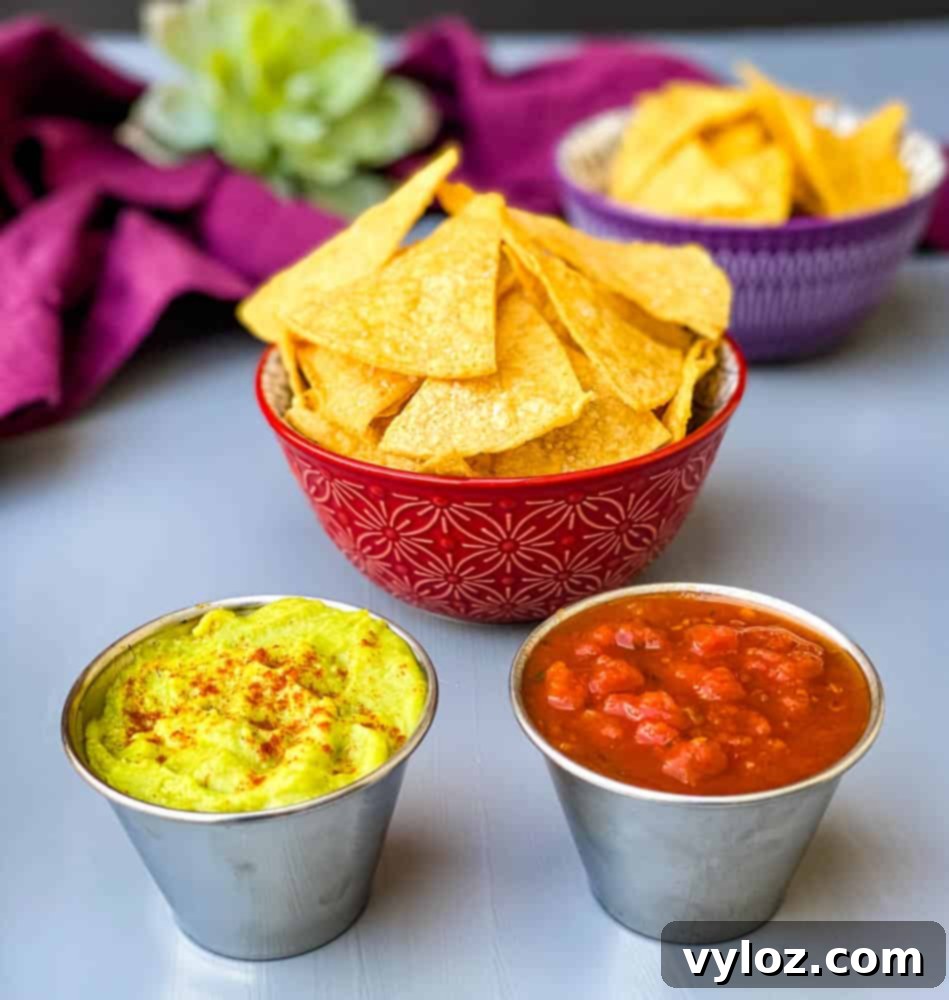 air fryer tortilla chips in a red bowl with guacamole and salsa