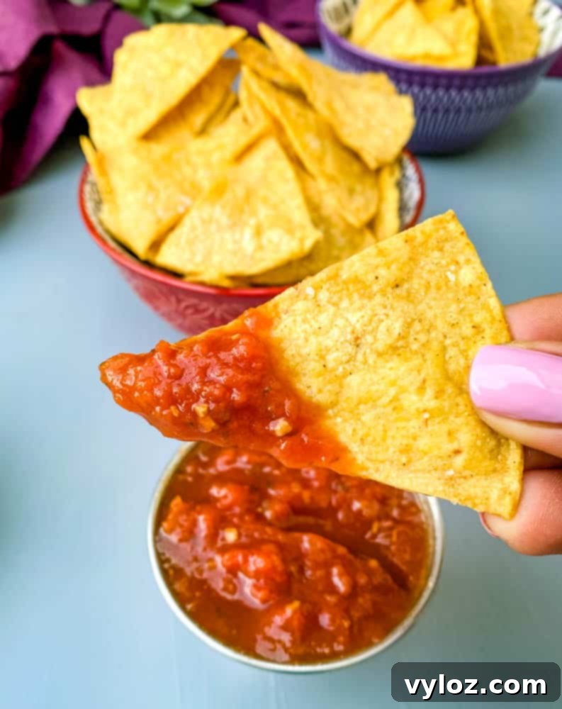 person holding air fryer tortilla chip with salsa