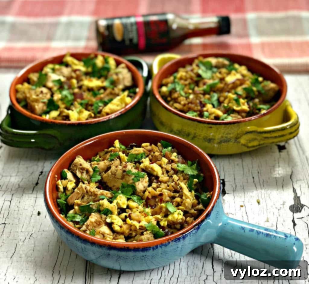 Delicious Keto Low-Carb Cauliflower Chicken Fried Rice in a serving dish, garnished with vibrant green onions and fresh cilantro