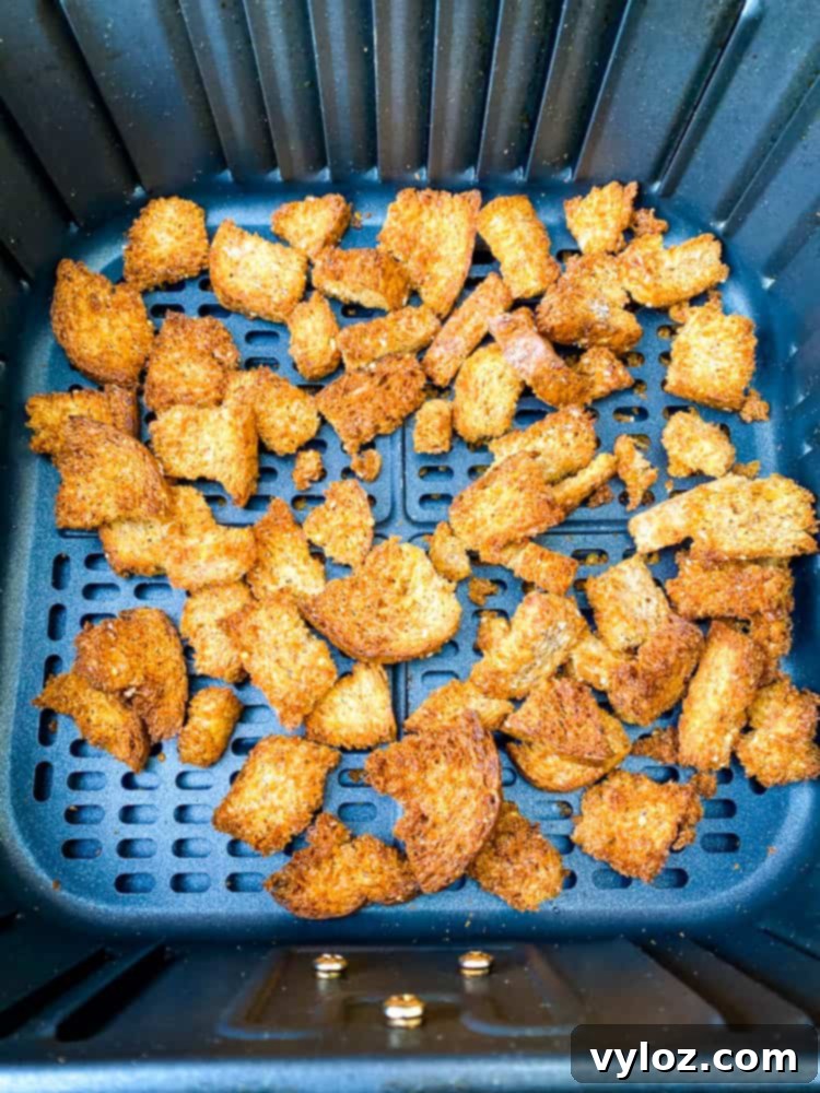Crispy Air Fryer Croutons 9 Ezekiel bread croutons cooking in an air fryer basket, showing a healthy alternative