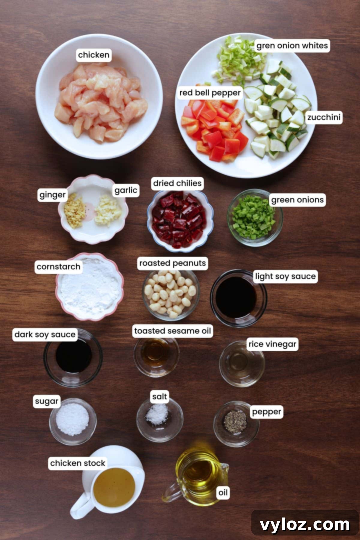 Ingredients for Kung Pao Chicken laid out in bowls: chicken, bell peppers, dried red chilies, peanuts, garlic, and sauce ingredients.