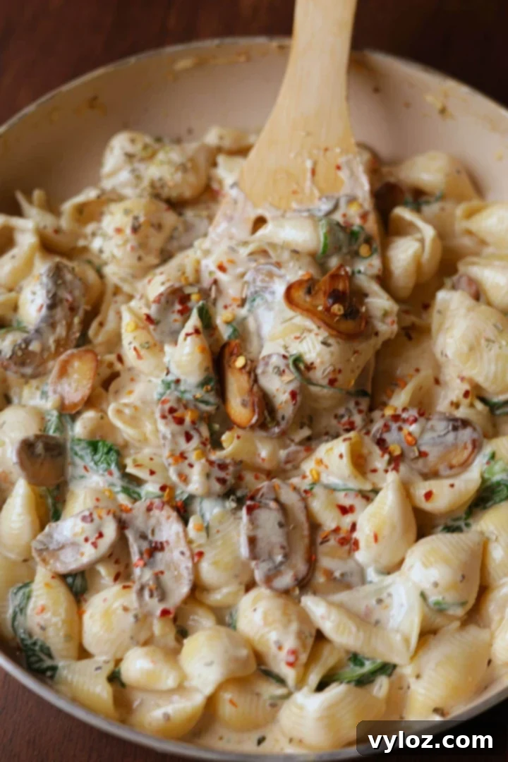 Velvety Mushroom and Spinach Pasta 2 Creamy spinach and mushroom pasta in an off-white pan, garnished with herbs.