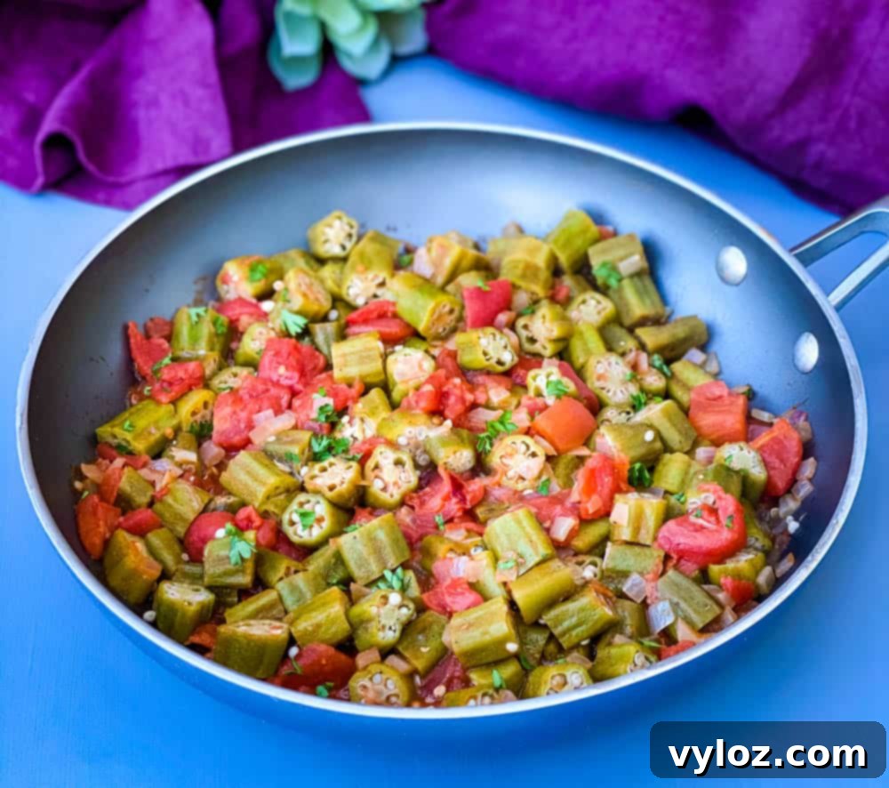 okra and tomatoes in a skillet with a purple napkin