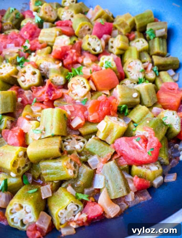 close up photo of okra and tomatoes in a pan