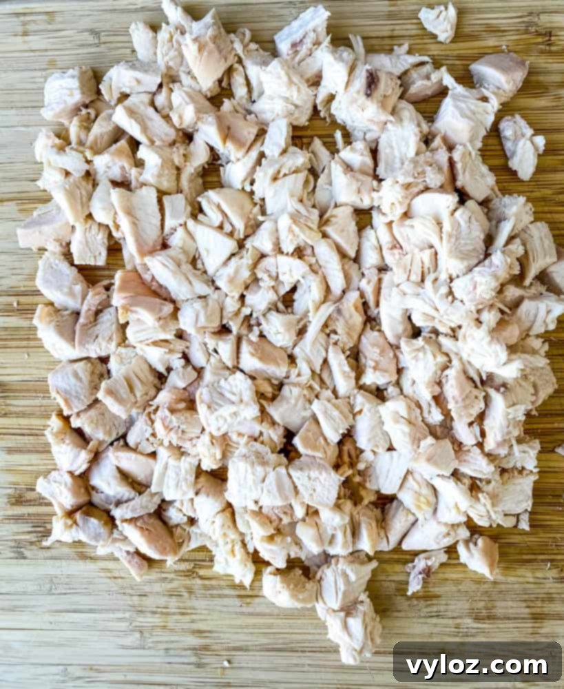 Effortless Keto Chicken Salad 6 cooked and cubed chicken breasts on a bamboo cutting board