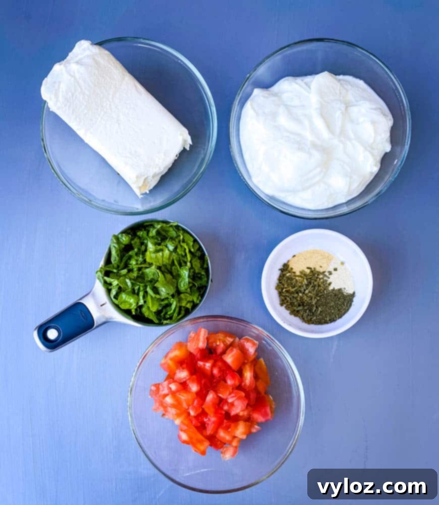 Ultimate Creamy BLT Dip 4 Individual bowls showcasing the fresh ingredients for a BLT dip: softened cream cheese, creamy Greek yogurt, finely shredded lettuce, bright red diced tomatoes, and a mix of homemade ranch seasoning.