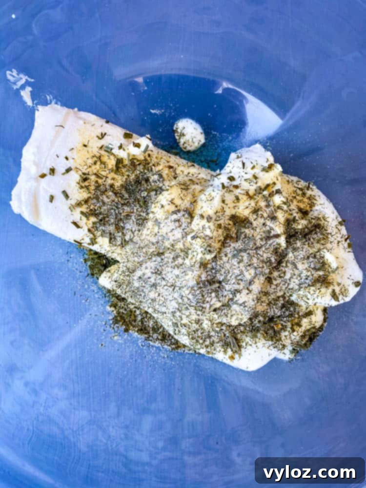 Ultimate Creamy BLT Dip 5 A glass bowl containing a creamy mixture of softened cream cheese and Greek yogurt, expertly blended with homemade ranch seasoning.