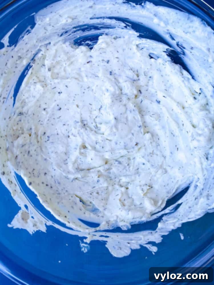 Ultimate Creamy BLT Dip 6 A close-up view of the creamy BLT dip in a clear glass bowl, showcasing its smooth texture before toppings are added.