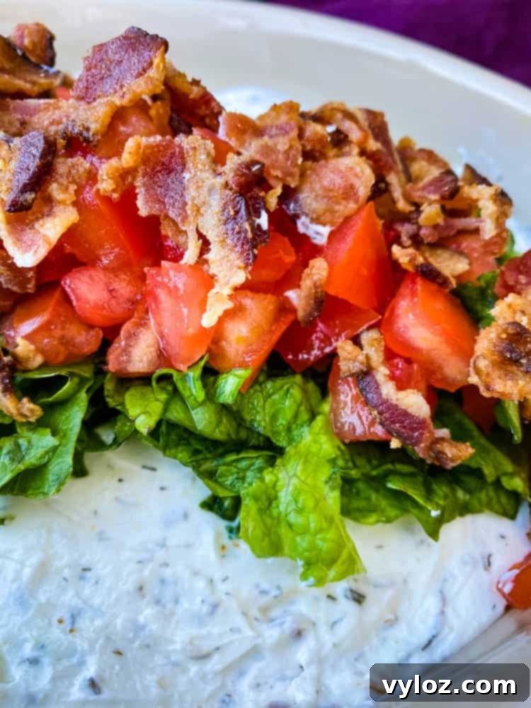 Ultimate Creamy BLT Dip 9 A beautifully presented BLT dip, topped with crisp lettuce, golden-brown bacon, and diced red tomatoes, ready to be enjoyed.
