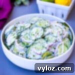 creamy cucumber salad with red onions in a white bowl