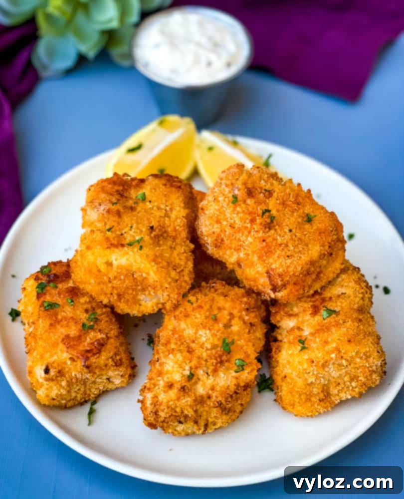 No-Fuss Air Fryer Fish 2 air fryer fish sticks on a white plate with tarter sauce and lemons