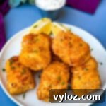 No-Fuss Air Fryer Fish 12 air fryer fish sticks on a white plate with tarter sauce and lemons