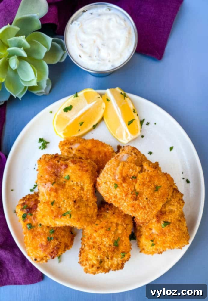 No-Fuss Air Fryer Fish 8 air fryer fish sticks on a white plate with tarter sauce and lemons