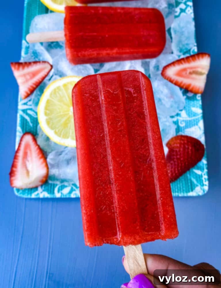person holding a sugar free strawberry lemon popsicle