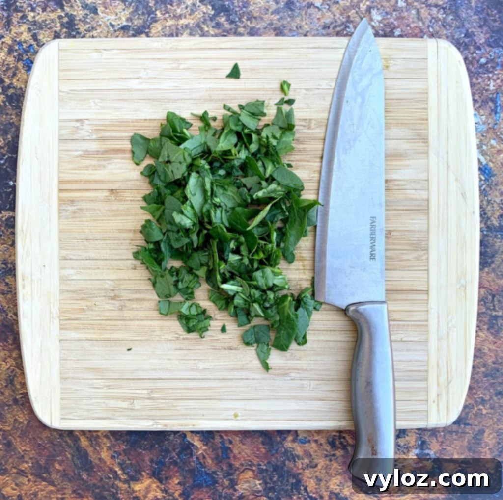 Creamy Spinach Stuffed Chicken Breast 4 Finely chopped fresh spinach on a wooden cutting board, ready for the stuffing.