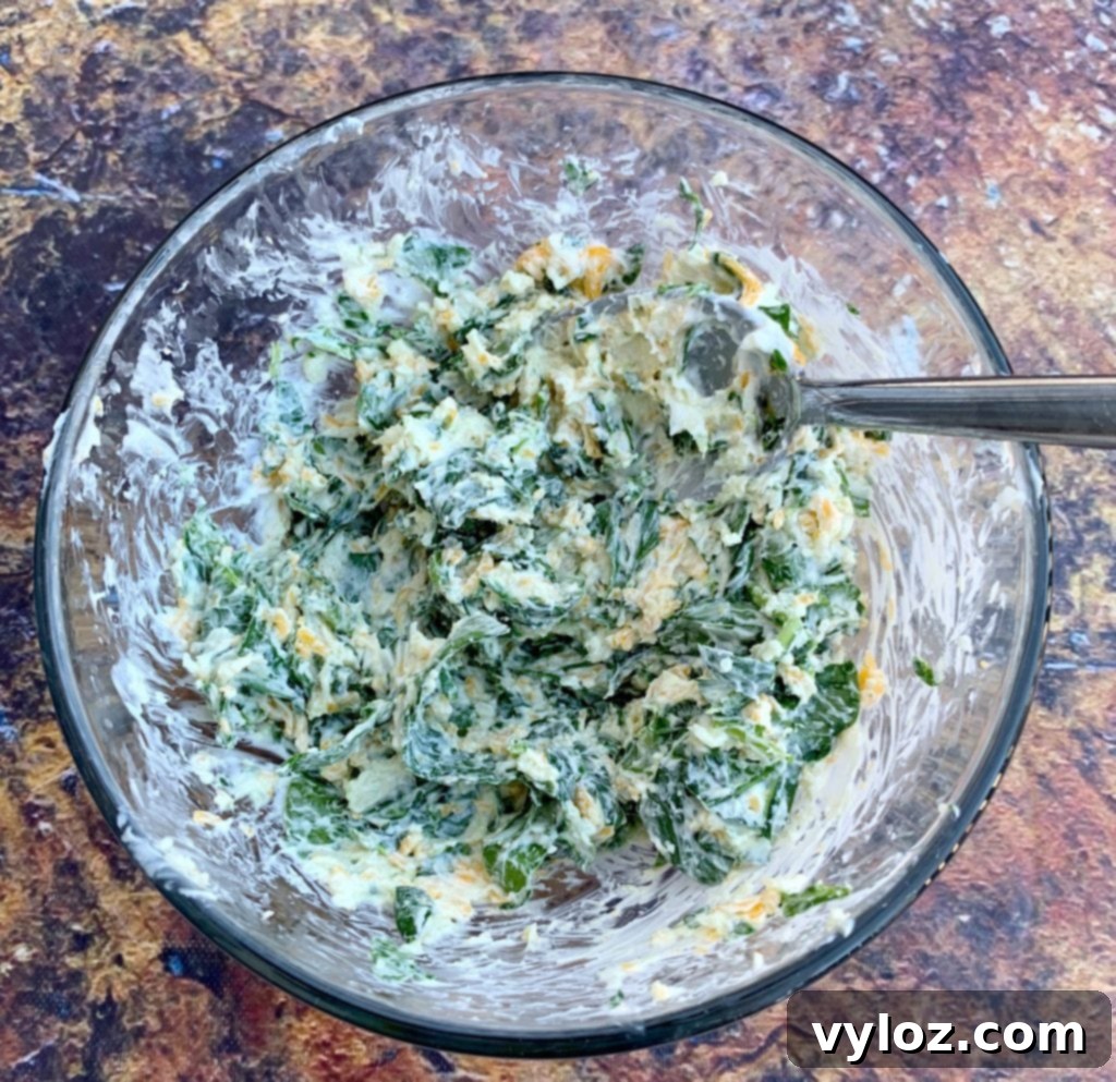 Creamy Spinach Stuffed Chicken Breast 6 A bowl filled with a creamy mixture of cream cheese, spinach, and grated cheddar, ready to be used as stuffing.
