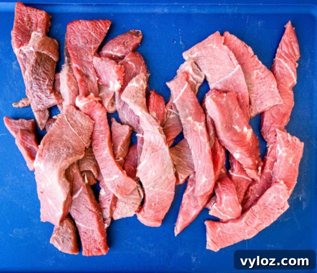 Thin, raw slices of sirloin tip steak arranged on a cutting board, prepared for marinating.