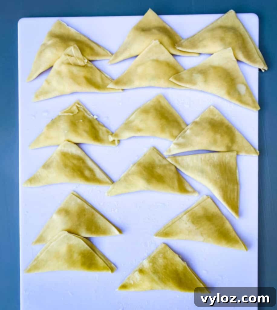 wontons folder in a triangle on a white cutting board