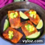 blackened salmon in a cast iron skillet topped with pineapple and avocado