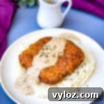 Southern Keto Chicken Fried Steak and Gravy 13 keto low carb chicken fried steak with country gravy on a bed of cauliflower mash on a white plate