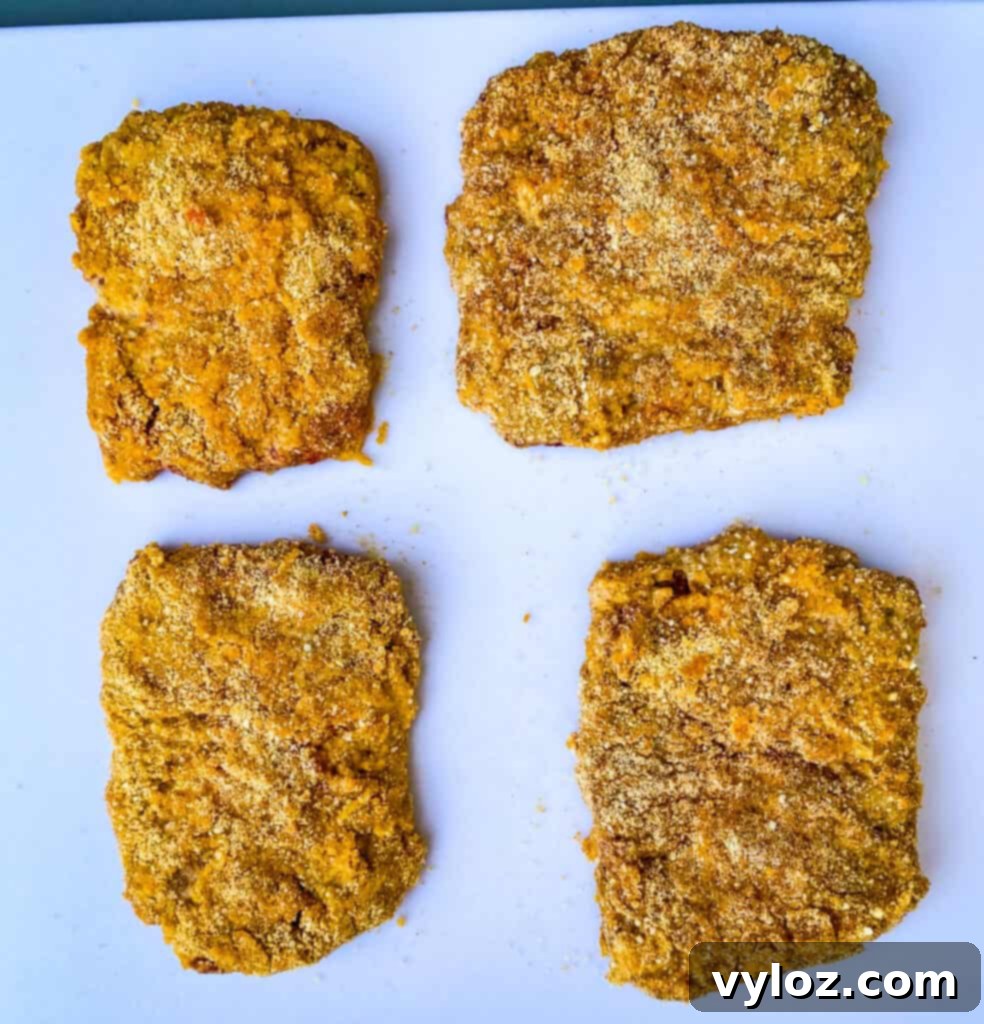 Southern Keto Chicken Fried Steak and Gravy 7 raw and bread keto chicken fried steaks on a white cutting board