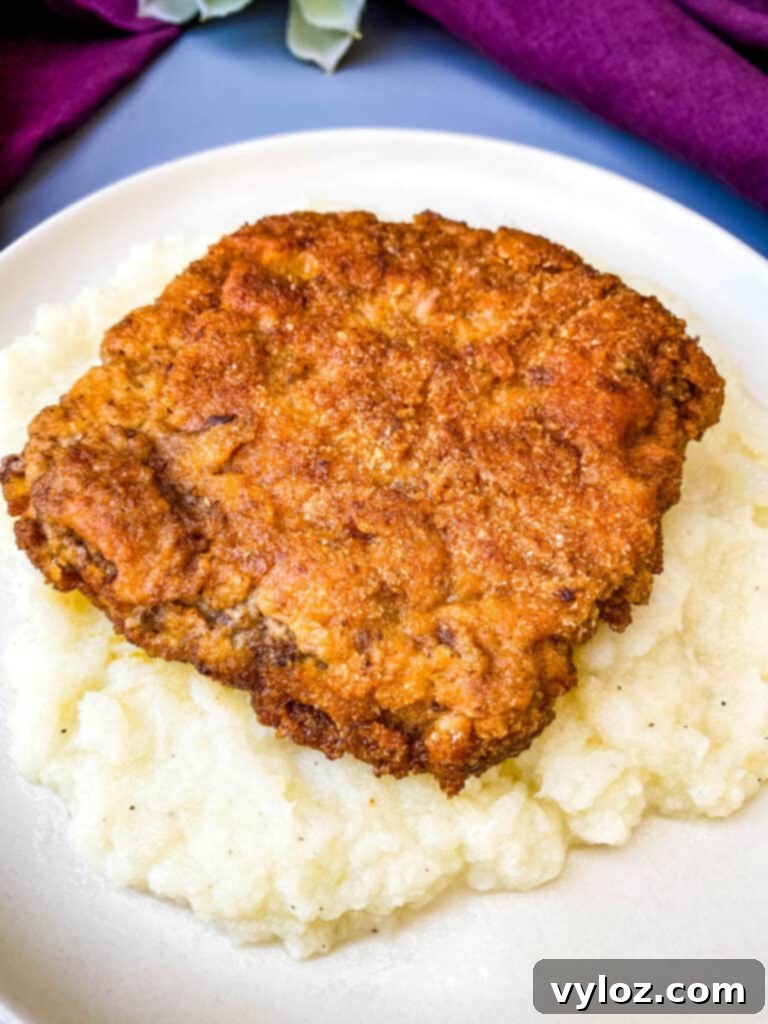 Southern Keto Chicken Fried Steak and Gravy 10 keto low carb chicken fried steak on a bed of cauliflower mash on a white plate