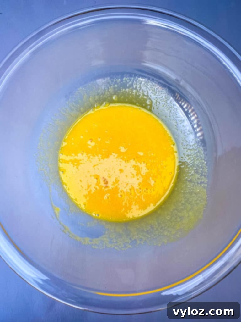 Effortless Keto Crème Brûlée 4 Egg yolks mixed with sweetener in a clear glass bowl, showcasing the creamy base for keto crème brûlée