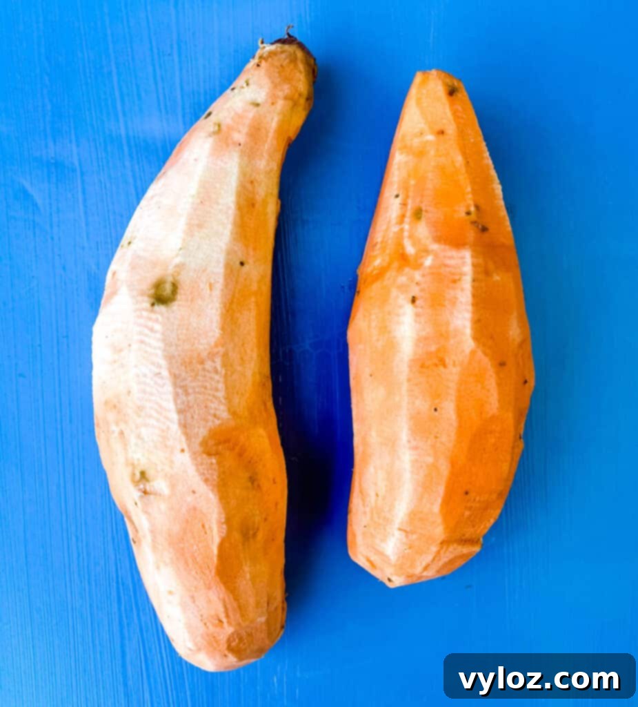 Crispy Air Fryer Sweet Potato Chips 4 Raw peeled sweet potatoes on a pristine white cutting board, prepared for the next step