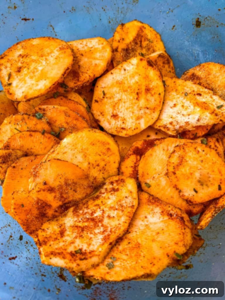 Crispy Air Fryer Sweet Potato Chips 7 Finely seasoned raw sweet potato chips artfully arranged in a clear glass bowl, poised for air frying