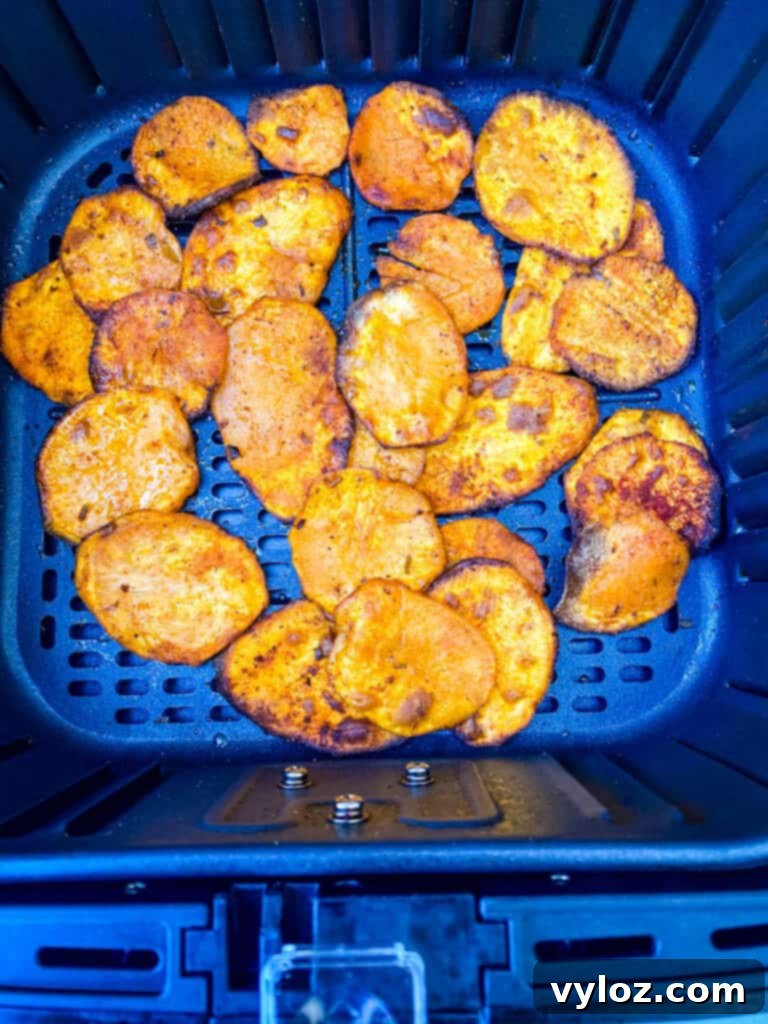 Crispy Air Fryer Sweet Potato Chips 9 Crispy sweet potato chips cooking within an air fryer basket, achieving a radiant golden hue