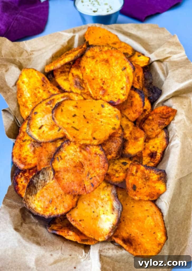 Crispy Air Fryer Sweet Potato Chips 10 A beautifully arranged platter of air fryer sweet potato chips, accompanied by a small bowl of savory dipping sauce, highlighting their appealing crispy texture