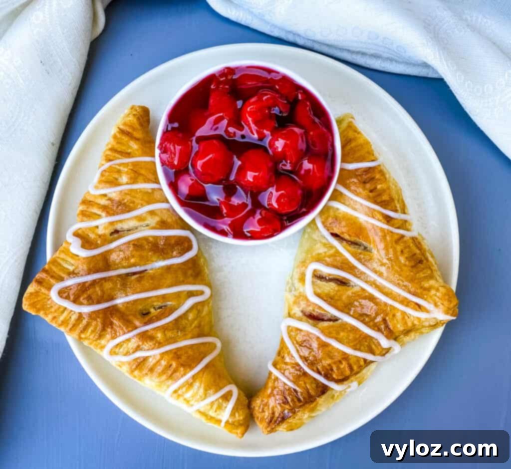 air fryer turnovers on a white plate with a bowl of cherries