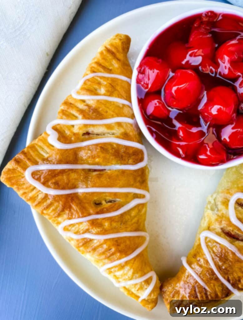 air fryer turnovers on a white plate with a bowl of cherries