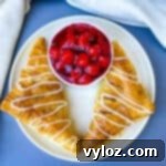 air fryer turnovers on a white plate with a bowl of cherries