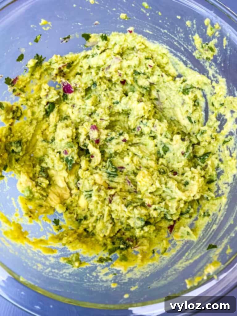 Creamy mashed avocado and egg yolk mixture in a glass bowl, perfectly blended and seasoned, resembling a savory guacamole.