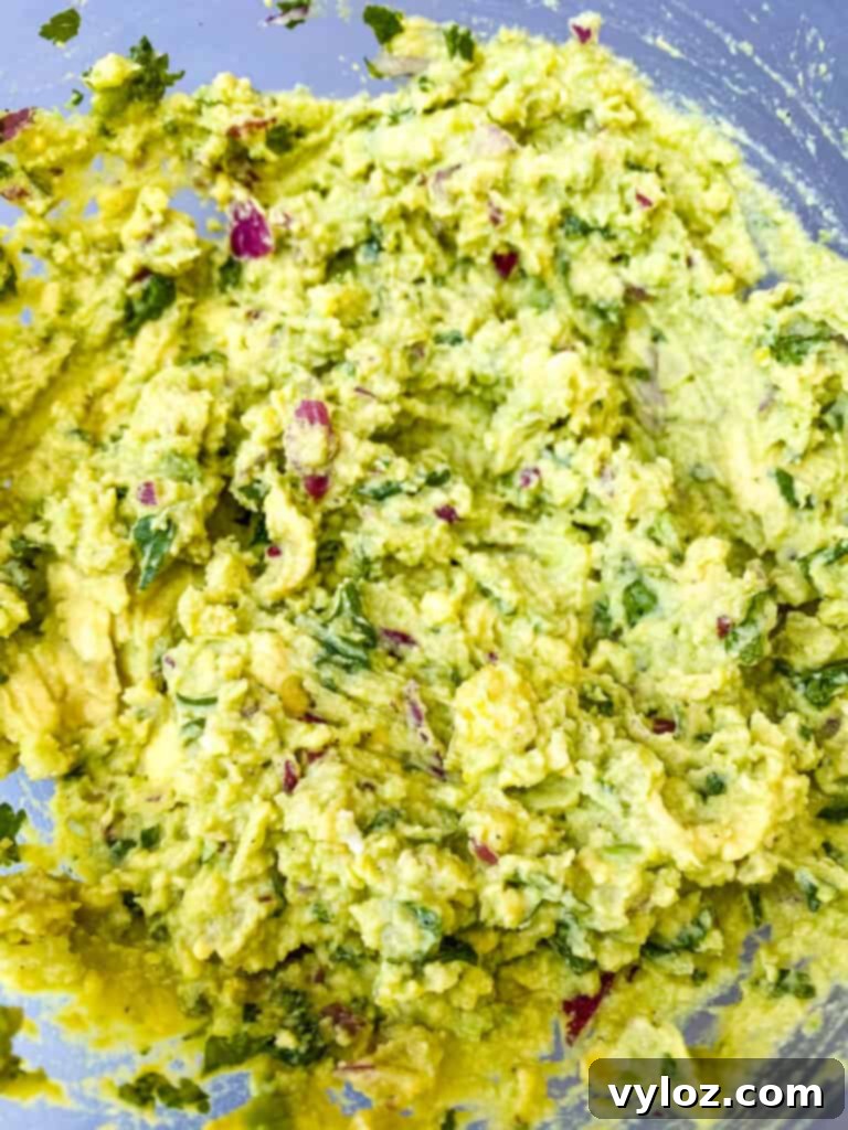 A close-up of the mashed guacamole-like filling in a glass bowl, showing its vibrant green color and creamy texture.