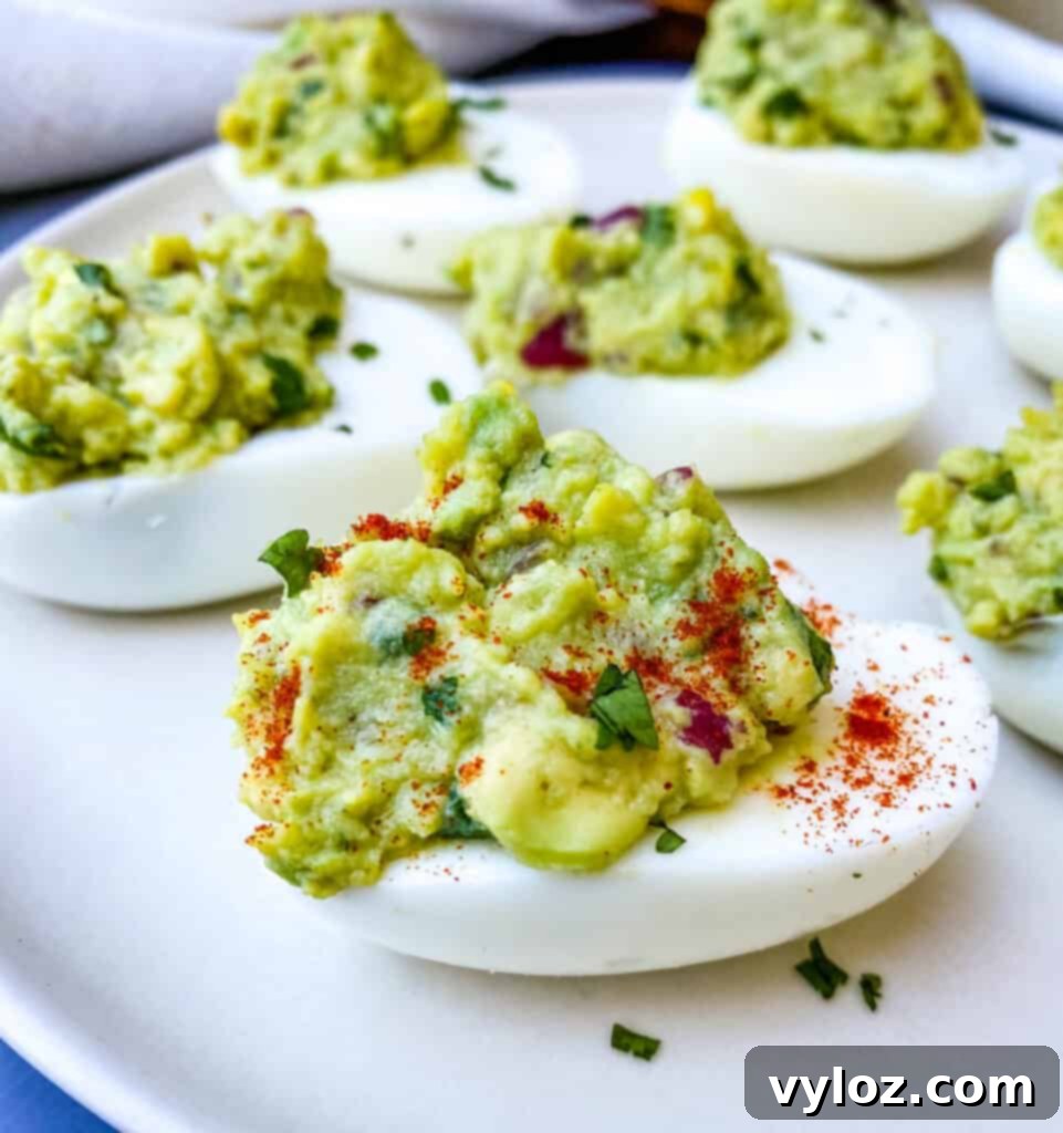 Avocado deviled eggs garnished with a sprinkle of paprika, presented on a platter.