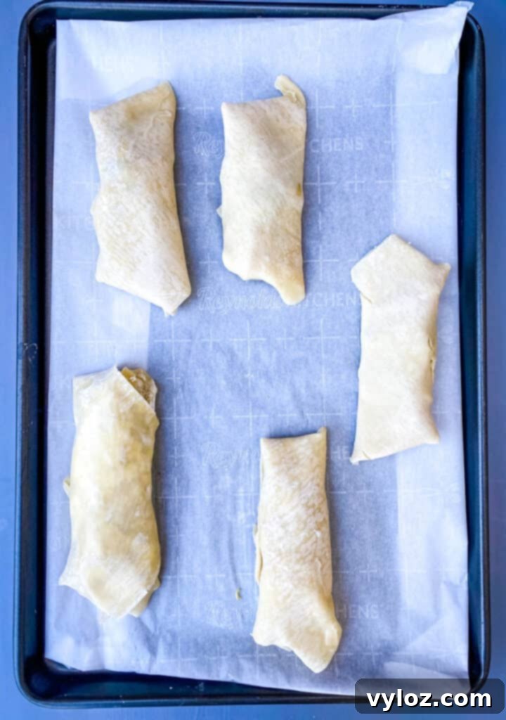 Baked shrimp egg rolls arranged on a sheet pan lined with parchment paper, perfectly golden and crispy.