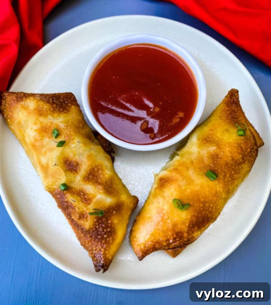 Delicious crispy shrimp egg rolls, freshly cooked and served on a plate with a side of sweet and sour dipping sauce.